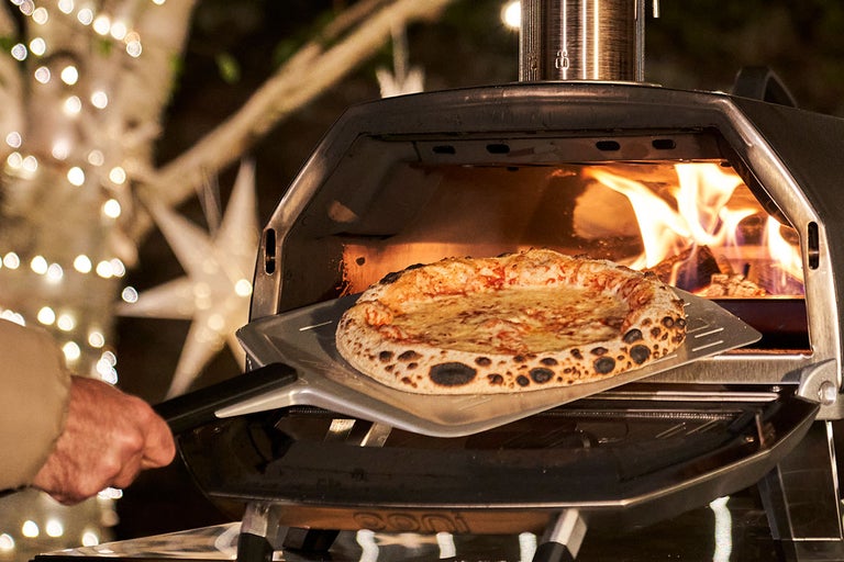 Pizzaoven met pizza op pizzaschep voor open vuur