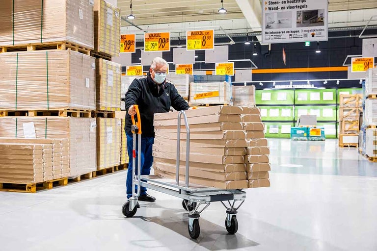 Een klant duwt een kar met goederen in een Hornbach bouwmarkt