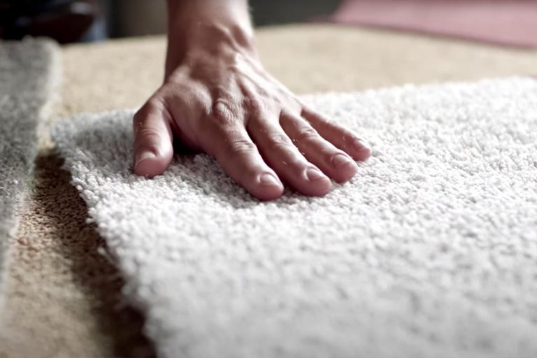 Hand die tapijt aanraakt voor kwaliteitscontrole