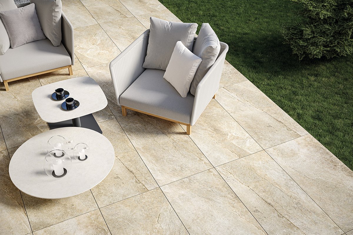 Modern terras met grootformaat tegels in natuursteenlook, loungestoelen, bijzettafels en een aangrenzend gazon.