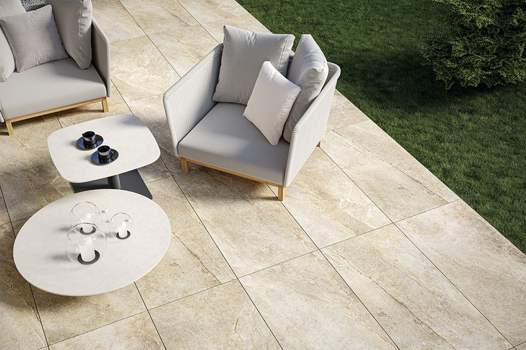 Modern terras met grootformaat tegels in natuursteenlook, loungestoelen, bijzettafels en een aangrenzend gazon.