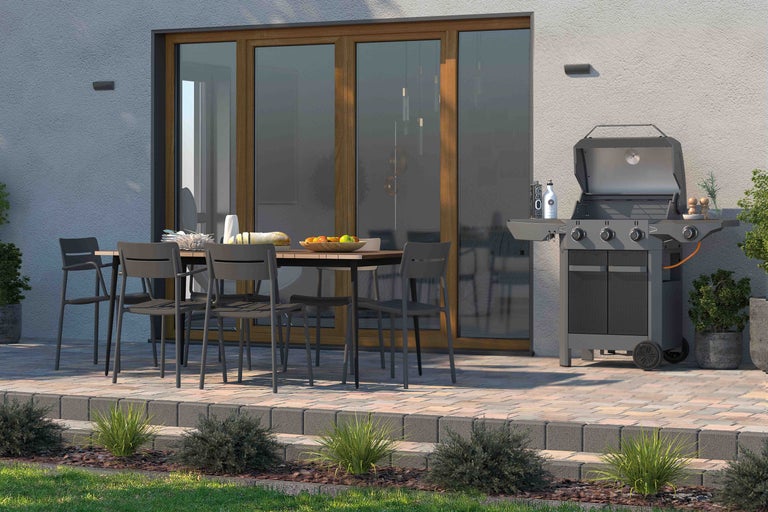 Terrasscène met barbecue, tuintafel en stoelen voor een huismuur