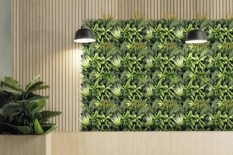 Decoratieve wand met kunstplanten, twee hanglampen en een pot met een kamerplant