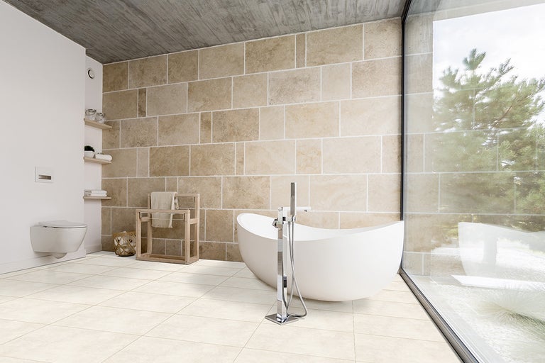 Lichte badkamer met vrijstaand bad, wandcloset en betegelde wanden.