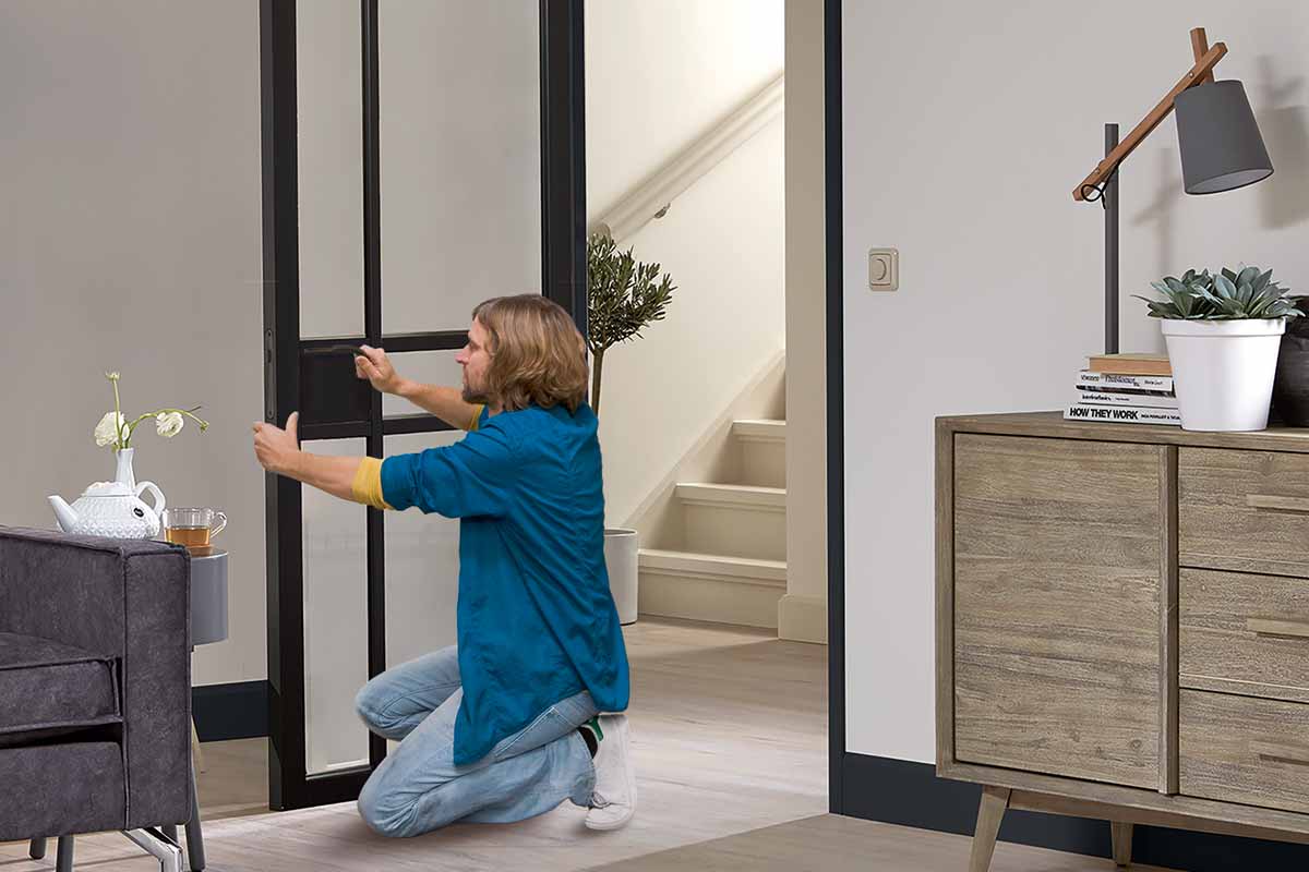 Man installeert binnendeur met glazen paneel in de woonkamer