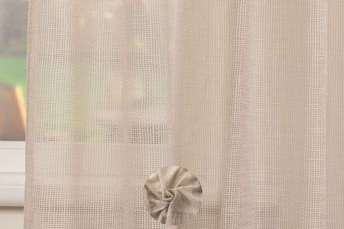 Gordijn in netoptiek met decoratieve stoffen bloem.
