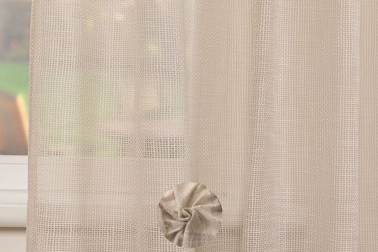 Gordijn in netoptiek met decoratieve stoffen bloem.