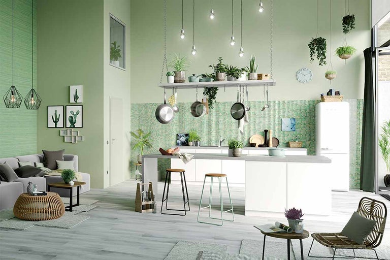 Lichte keuken met kookeiland, barkrukken en een woongedeelte met een bank.