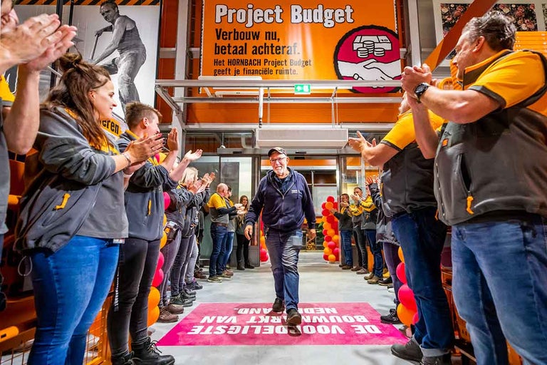 Een man loopt door een erehaag van klappende Hornbach-medewerkers.