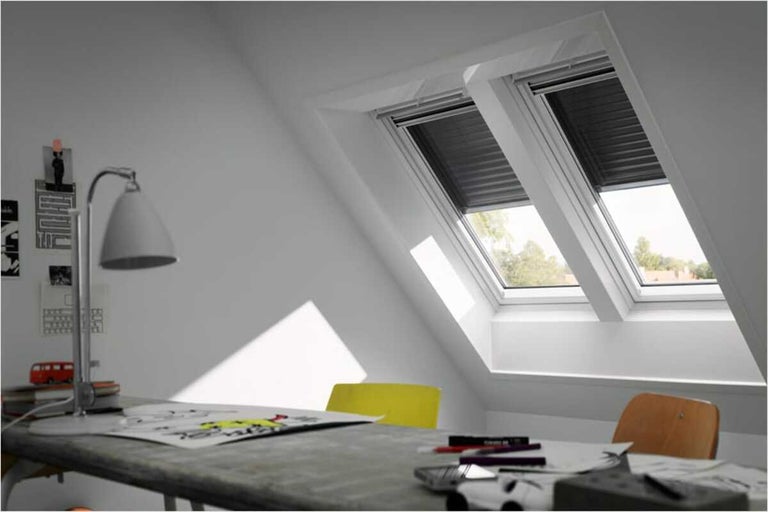 Twee dakramen met rolluiken in een werkkamer op zolder.