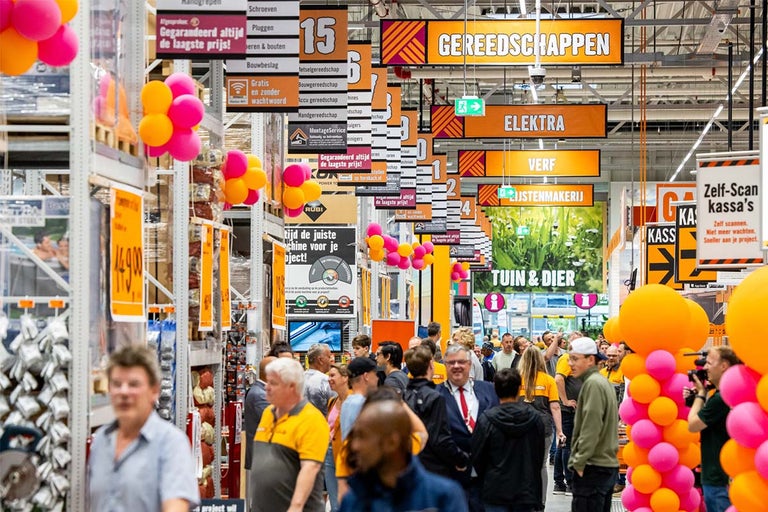 Interieurfoto van een Hornbach bouwmarkt met klanten, schappen en borden met aanduidingen van verschillende productcategorieën