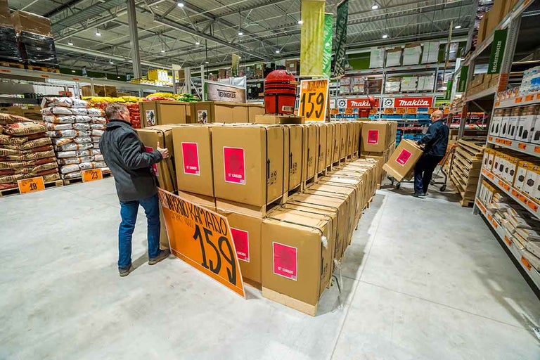In een Hornbach-bouwmarkt staan medewerkers voor een rij verpakte grills en bereiden deze voor de verkoop voor.