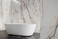 Vrijstaand bad in een badkamer met marmeren wanden en een donker aanrecht Vrijstaand bad in een badkamer met marmeren wanden en een donker aanrecht