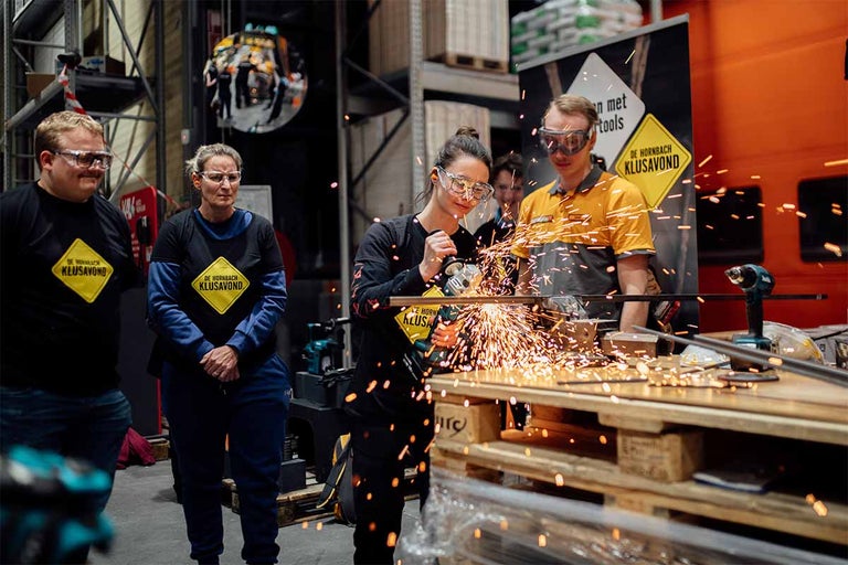 Persoon snijdt metaal met een haakse slijper in een bouwmarkt, vonken vliegen er vanaf.