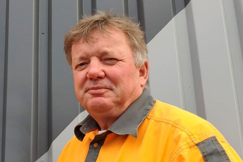 Portret van een man in werkkleding voor een wand