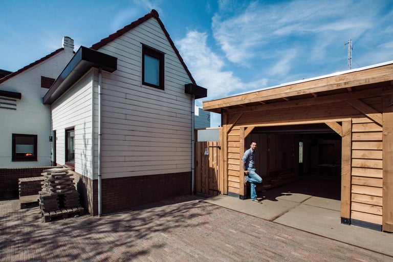Een eengezinswoning met een houten garage onder een blauwe lucht