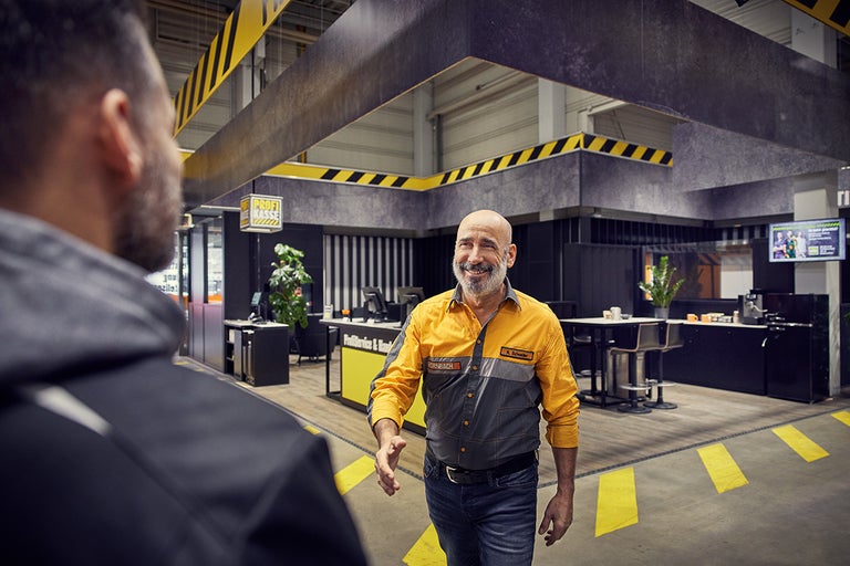Een Hornbach-medewerker begroet een klant in de professionele servicezone van de winkel.