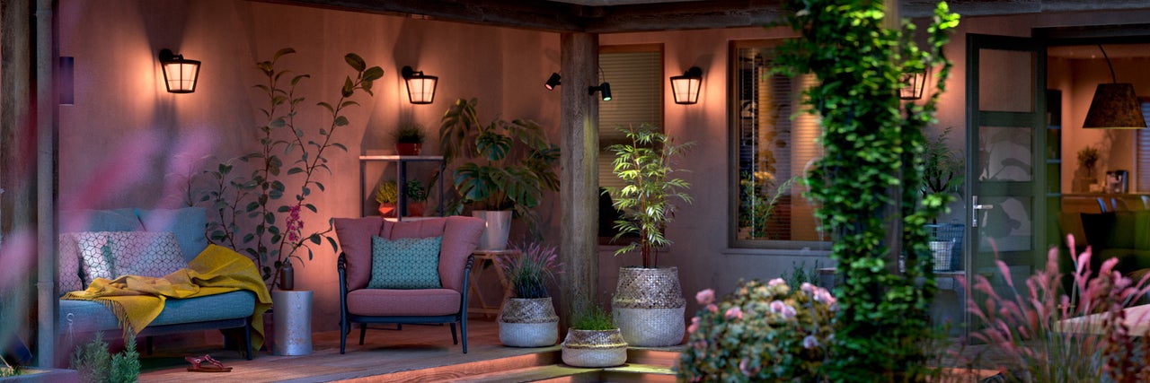 Sfeervolle terrasopstelling met tuinmeubelen, planten en buitenverlichting voor een gezellige ambiance