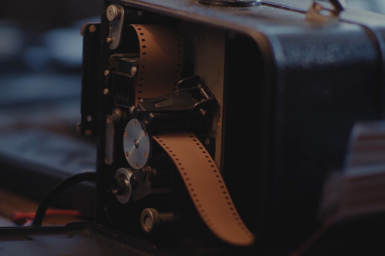 Historische filmprojector met filmstrook in de behuizing.