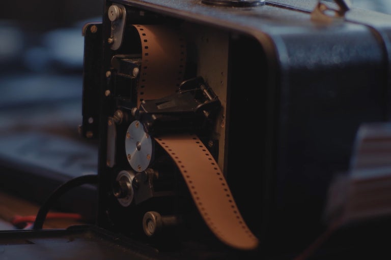 Historische filmprojector met filmstrook in de behuizing.