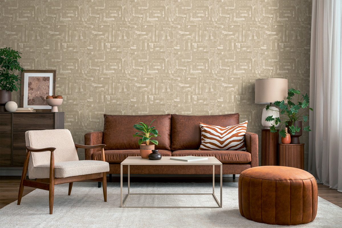 Lichte, georganiseerde woonkamer met behang met geometrisch patroon, bruine leren bank, lichte fauteuil, salontafel en tapijt.