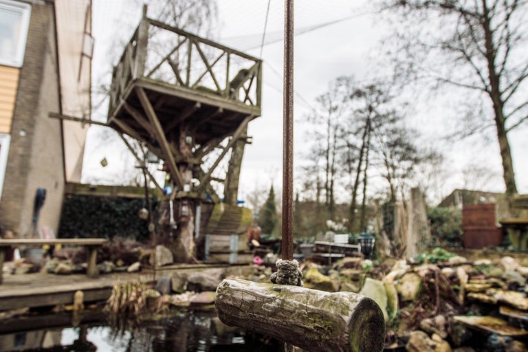 Buitenshot met een boomhut, een schommel en een vijver in een tuin.
