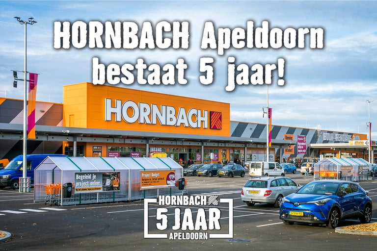 Buitenaanzicht van de Hornbach bouwmarkt in Apeldoorn ter gelegenheid van het vijfjarig jubileum met parkeerplaats en winkelwagenstallingen.