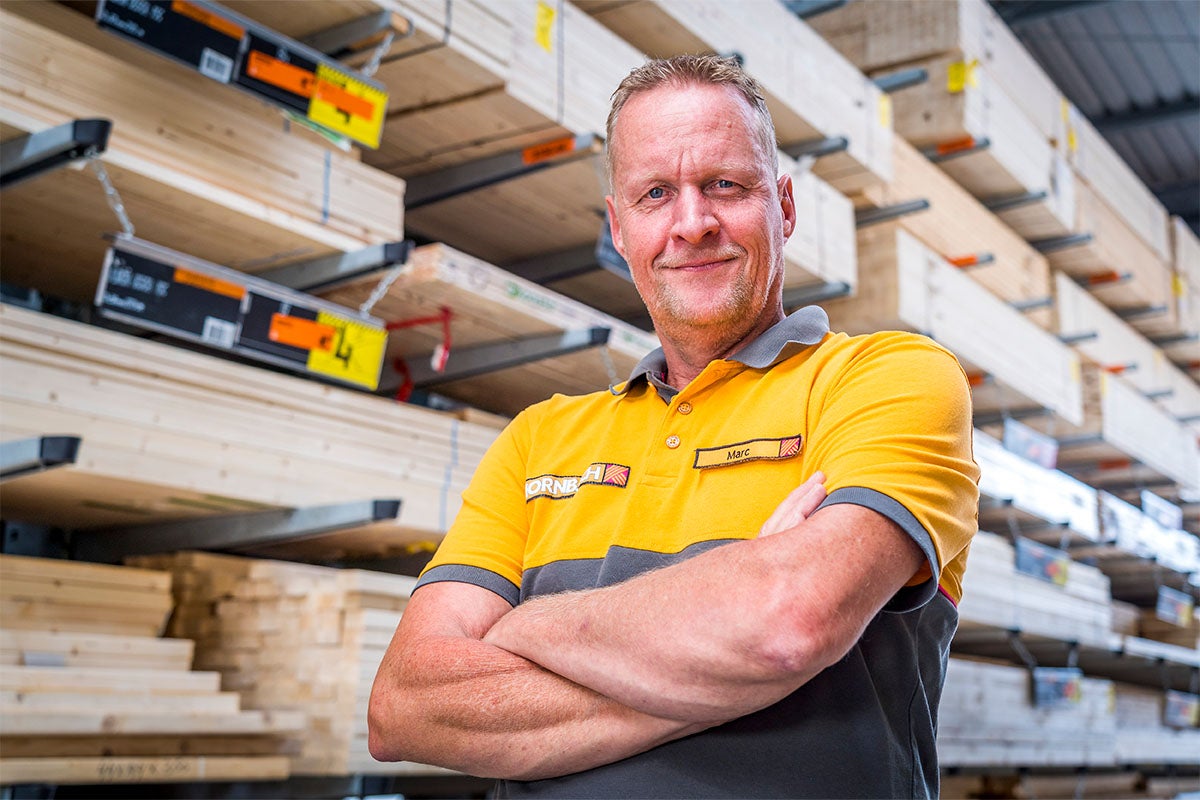 Een Hornbach medewerker staat voor houten rekken.