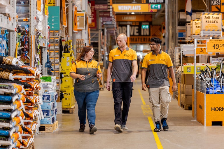 Drie Hornbach medewerkers lopen door een gang in de winkel.