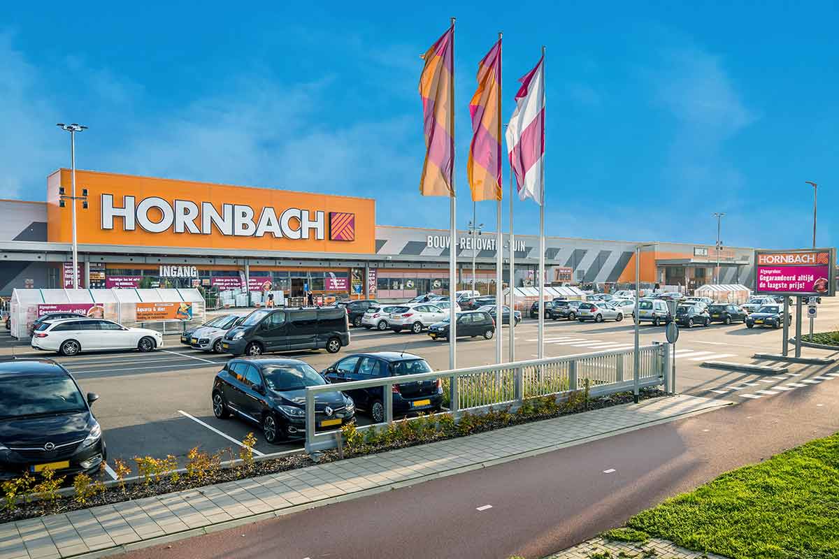 Buitenaanzicht van een Hornbach bouwmarkt met parkeerplaats en vlaggen
