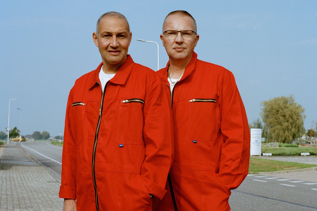 Twee mannen in overalls staan op straat