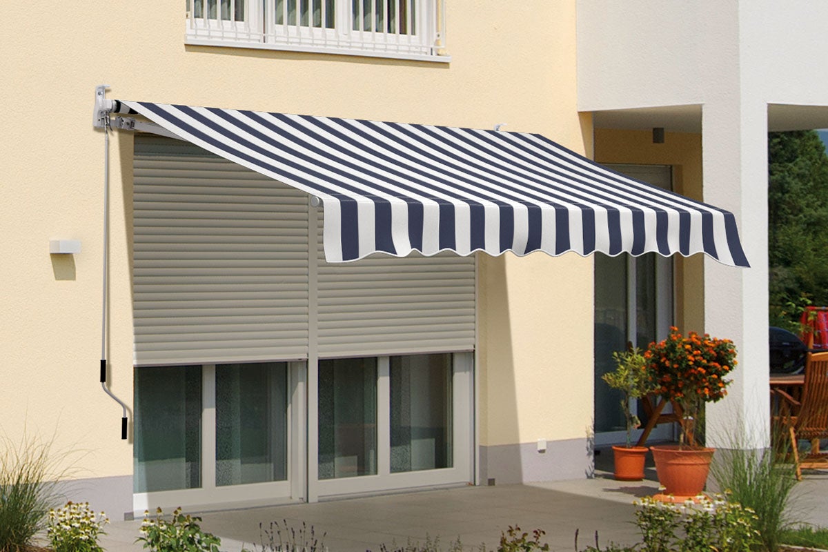 Gestreept knikarmscherm met handzwengel, gemonteerd op een lichte gevel boven een terras met planten.