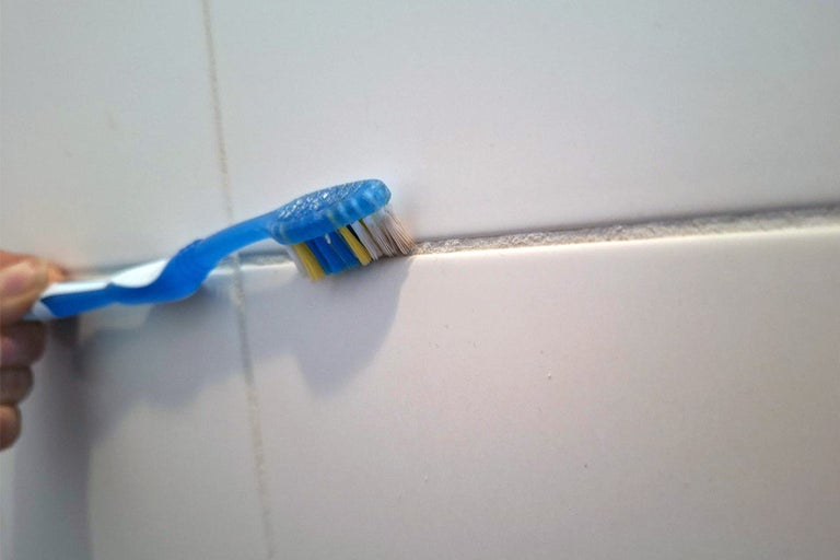 Een tandenborstel reinigt tegelvoegen.