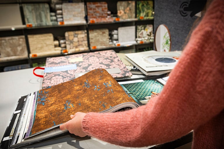 Vrouw bekijkt behangstalenboeken in de Hornbach-vestiging.