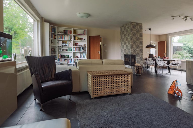 Woonkamer met bank, fauteuil, boekenkast, salontafel en eettafel