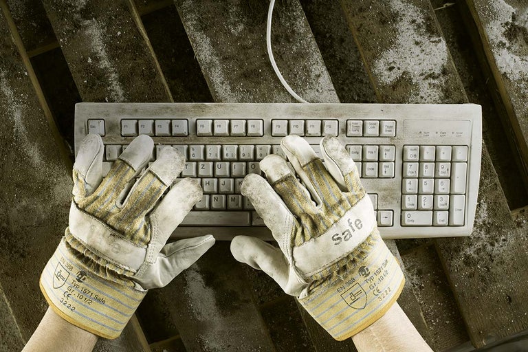 Een vuil toetsenbord met twee handen die vuile werkhandschoenen dragen