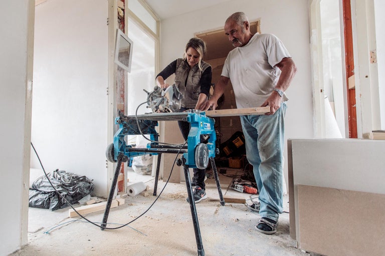 Twee mensen werken met een verstekzaag in een kamer.