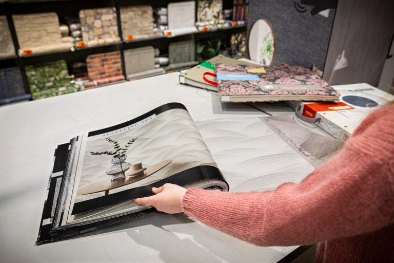 Een persoon bladert door een behangstalenboek met de titel Sparkling Sea in een Hornbach-winkel.