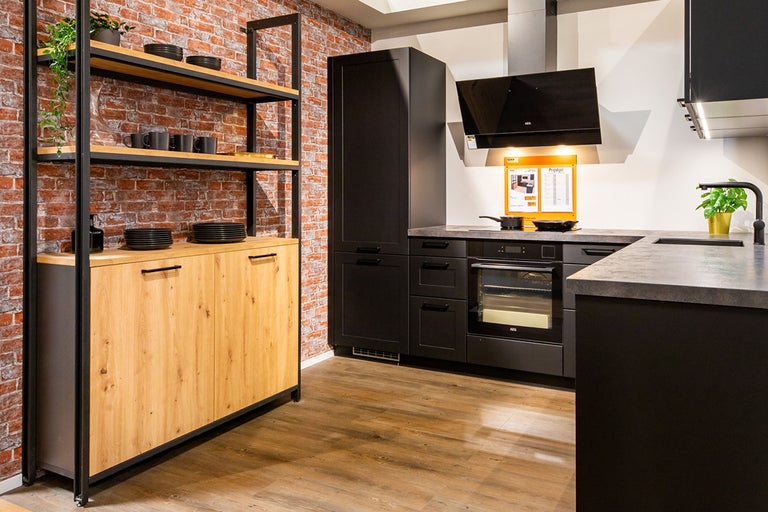 Keukenscène met rekken, keukenkasten, afzuigkap en spoelbak in een ruimte met bakstenen muur