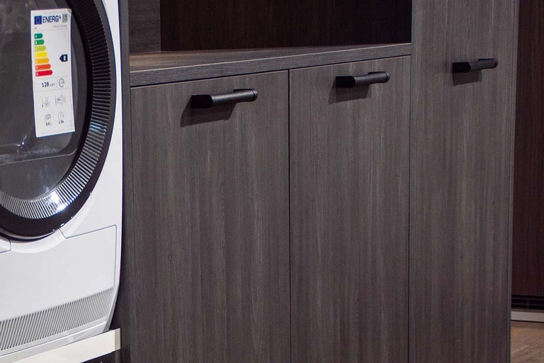 Wasmachine naast kast met deur en handgreep