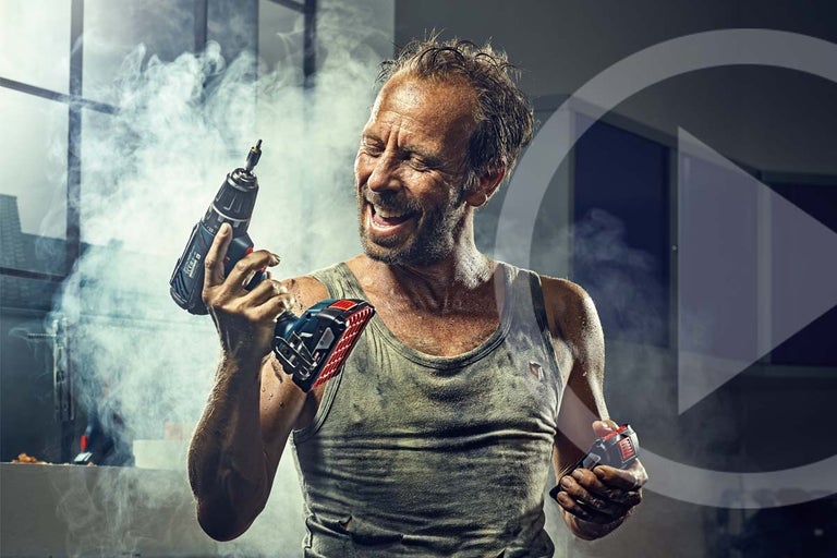 Een man houdt een accuschroefboormachine en een accu in zijn hand