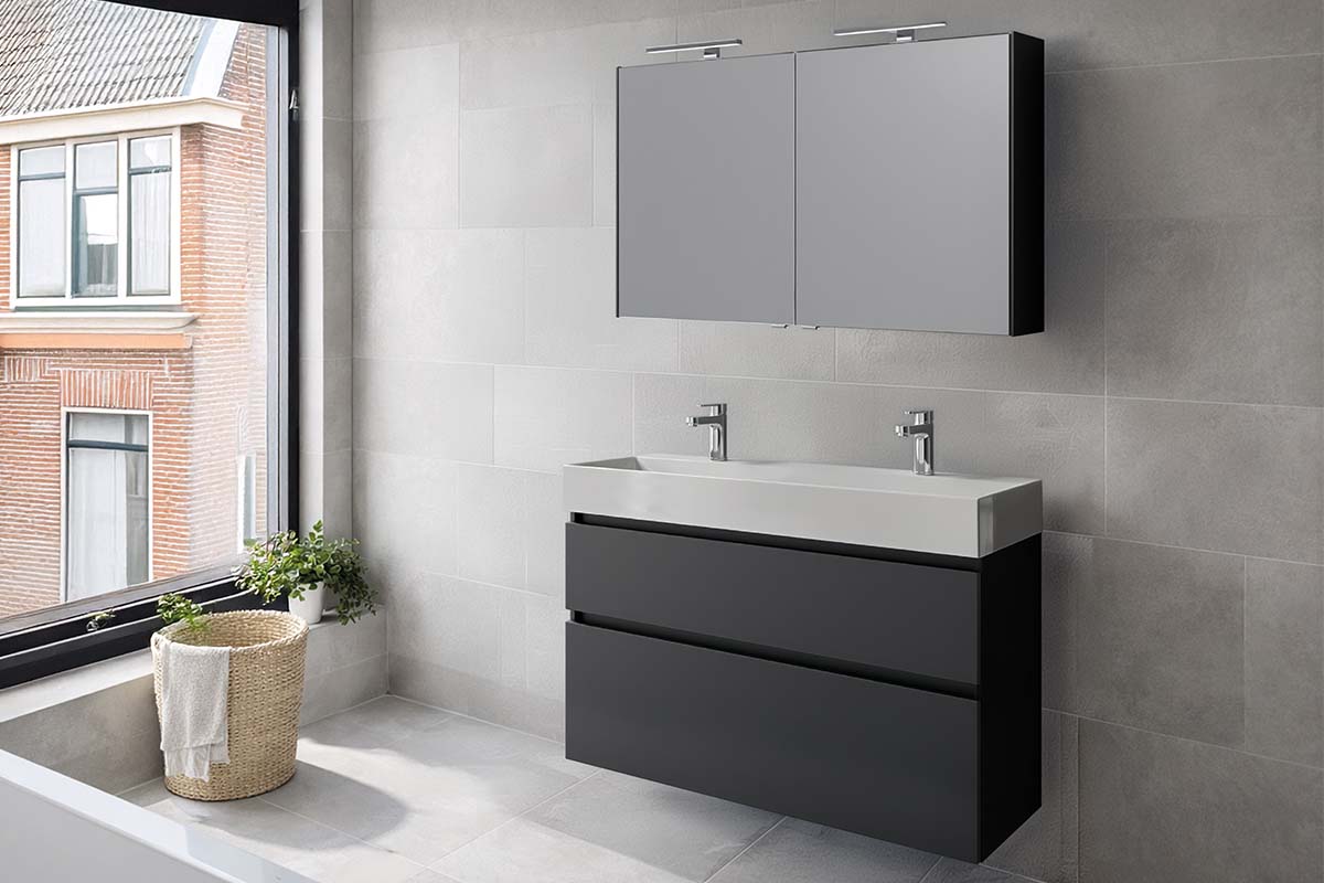 Moderne badkamer met donkergrijs dubbel wastafelmeubel, witte wastafel met twee kranen en een spiegelkast met verlichting.