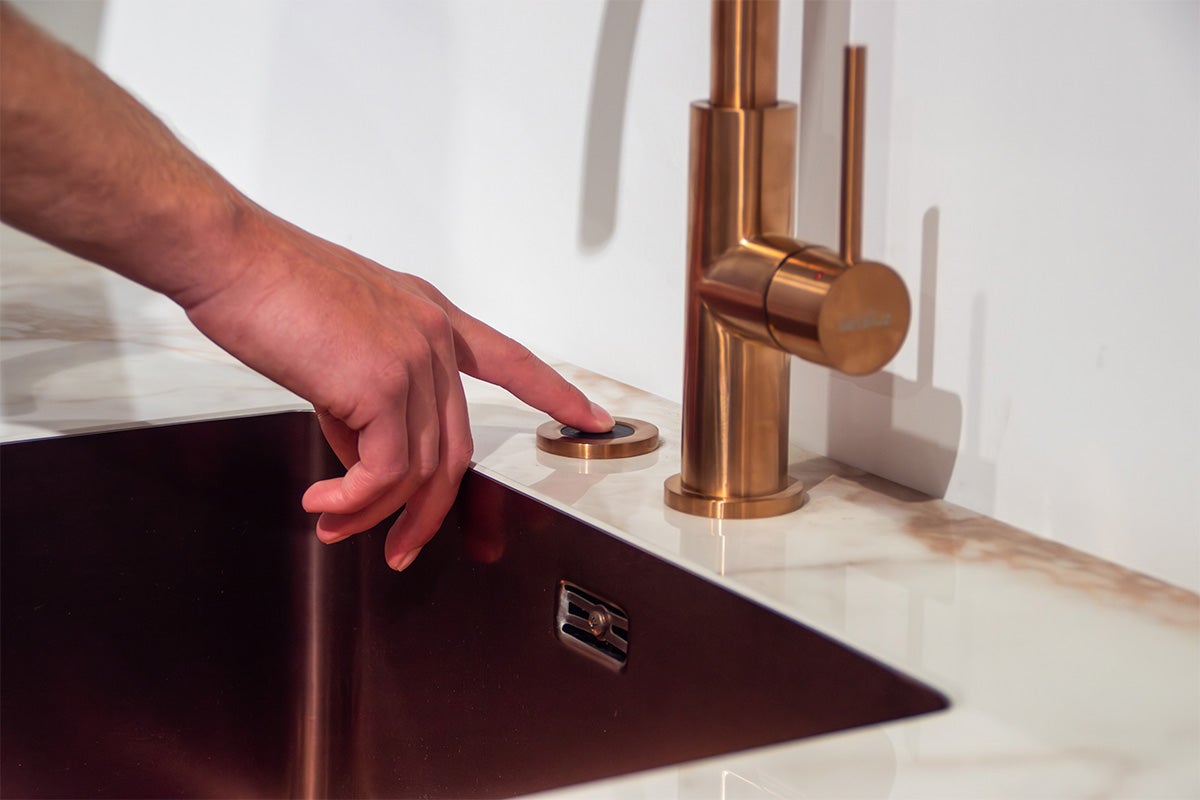 Hand bedient knop op aanrechtblad naast een kraan