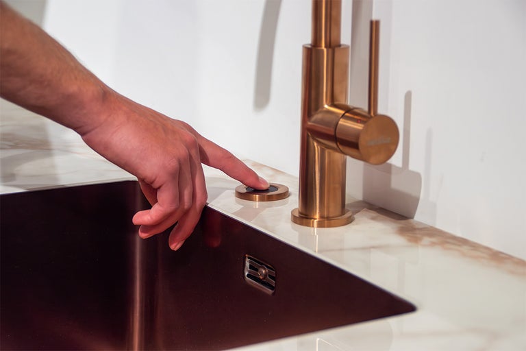 Hand bedient knop op aanrechtblad naast een kraan