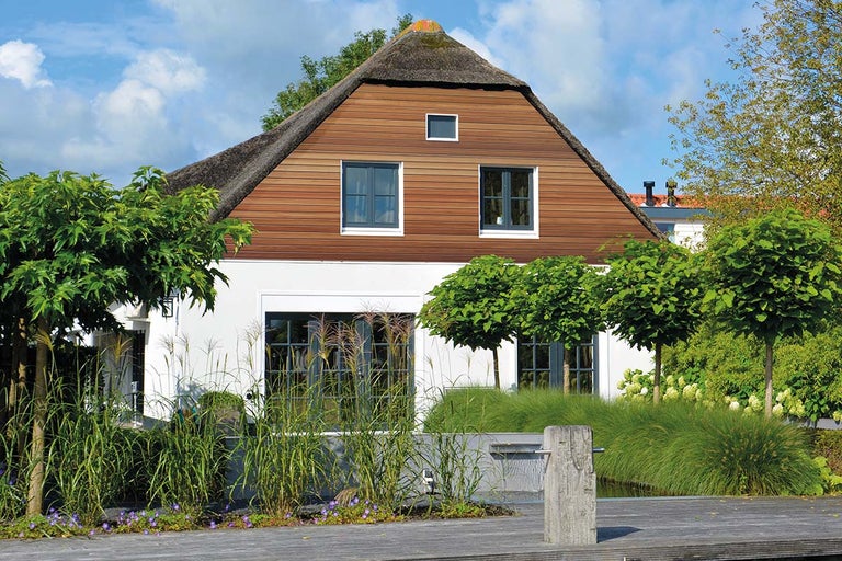 Huis met rieten dak, houten gevelbekleding en tuin