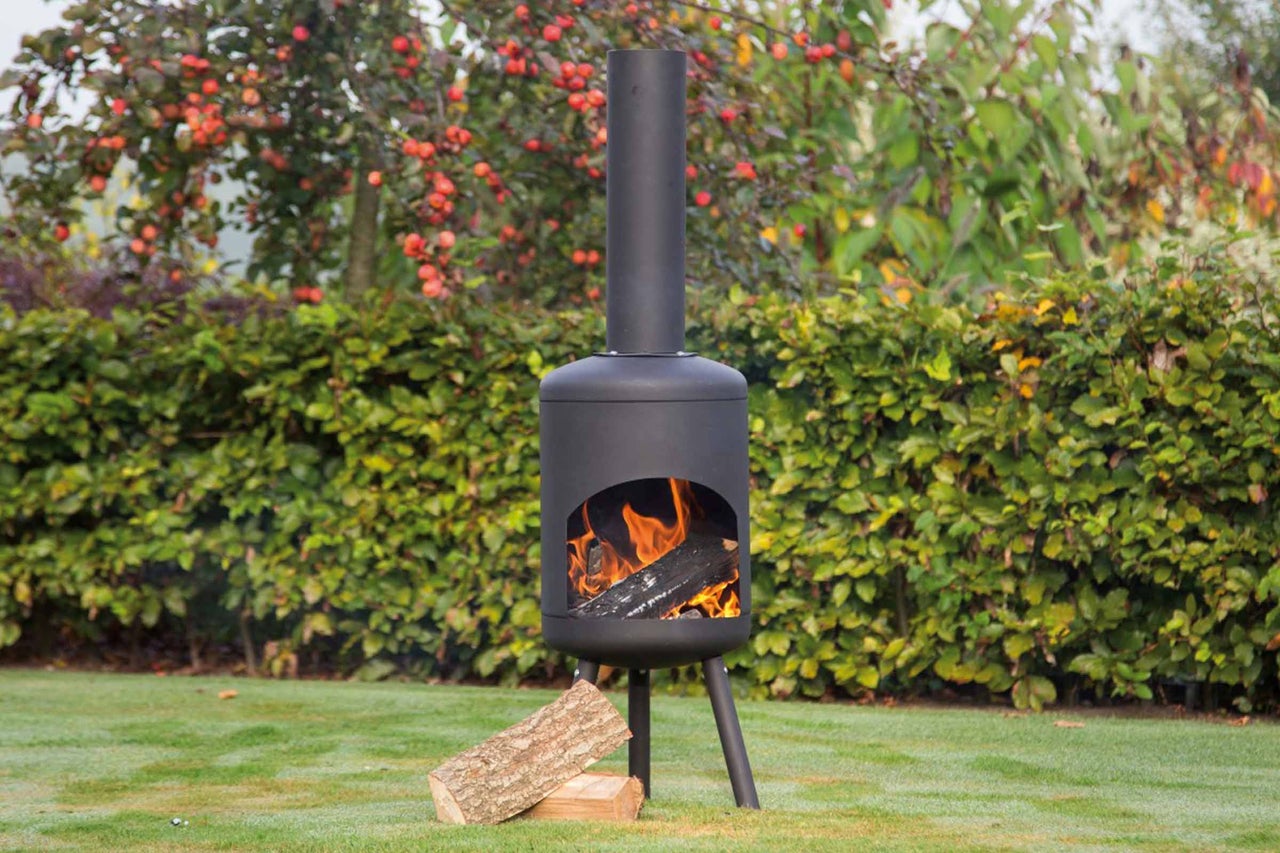 Tuinscene met brandende stalen tuinhaard en brandhout
