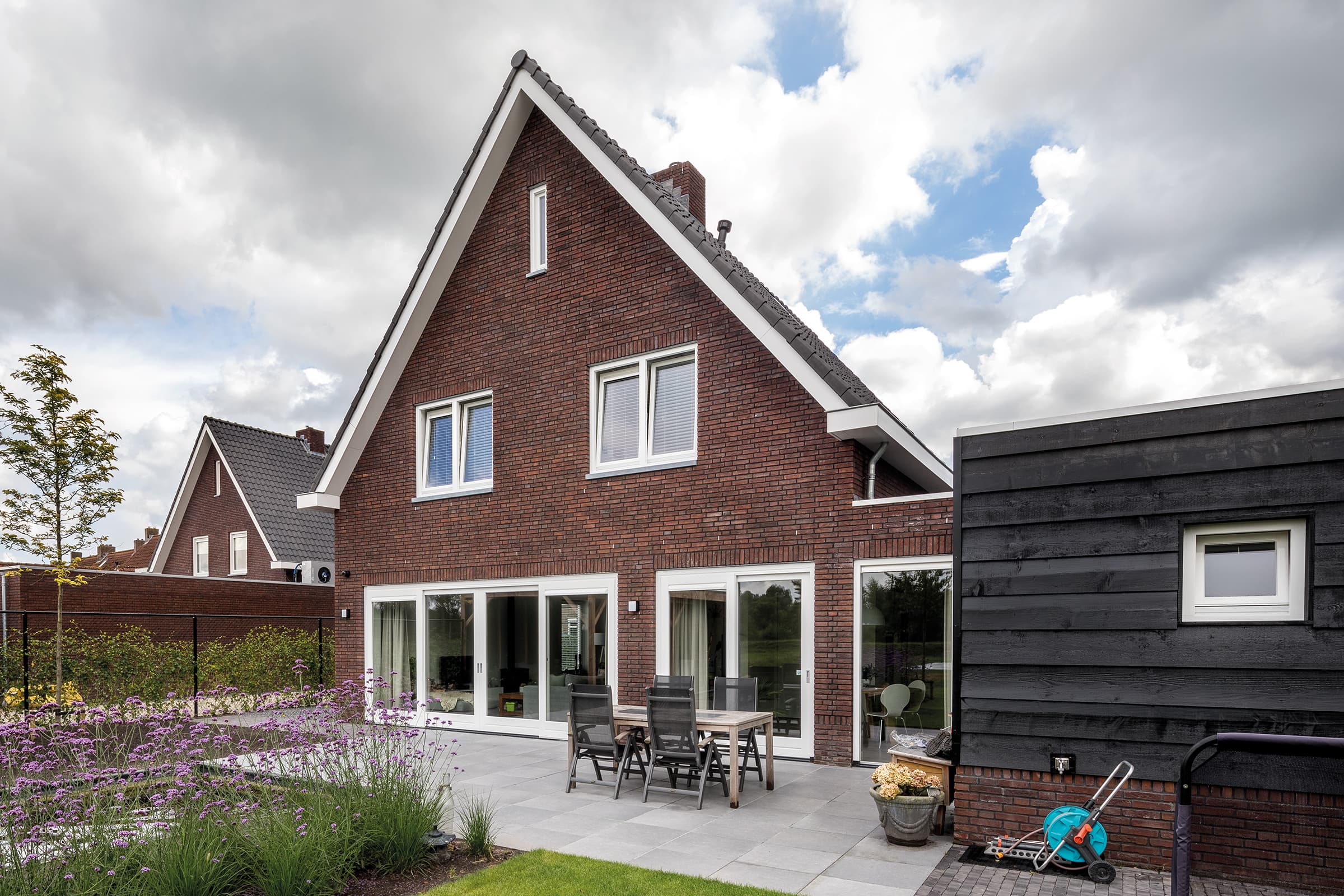 Een huis met een terras, een tafel en stoelen buiten