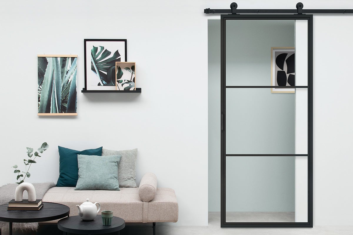 Woonkamer met schuifdeur, bank, salontafel en decoraties aan de muur.