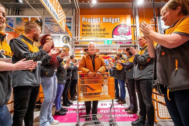 Klant duwt winkelwagen in Hornbach-vestiging terwijl medewerkers applaudisseren
