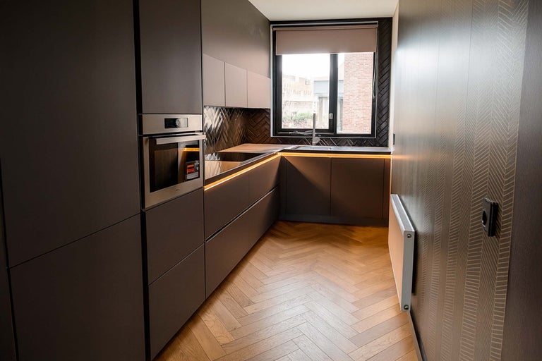 Moderne keuken met inbouwoven, raam en parketvloer